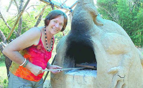 Robyn feeding the dragon, a wood-fired oven made from mud, sand and bamboo leaves. Robyn feeding the dragon, a wood-fired oven made from mud, sand and bamboo leaves.