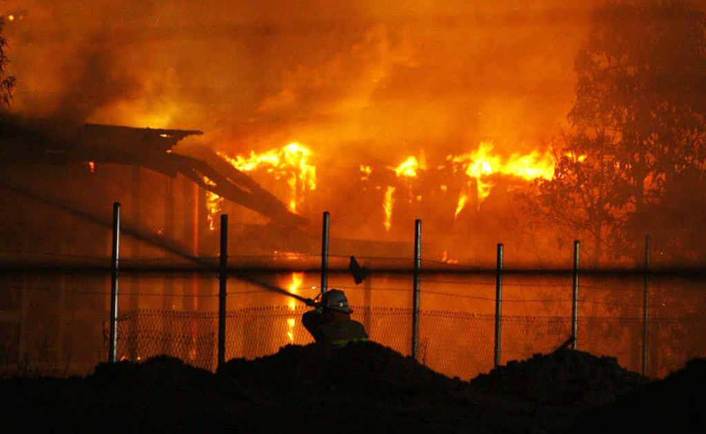 A firefighter hoses the flames which engulfed buildings at the old North Ipswich Railway Workshops. A firefighter hoses the flames which engulfed buildings at the old North Ipswich Railway Workshops.