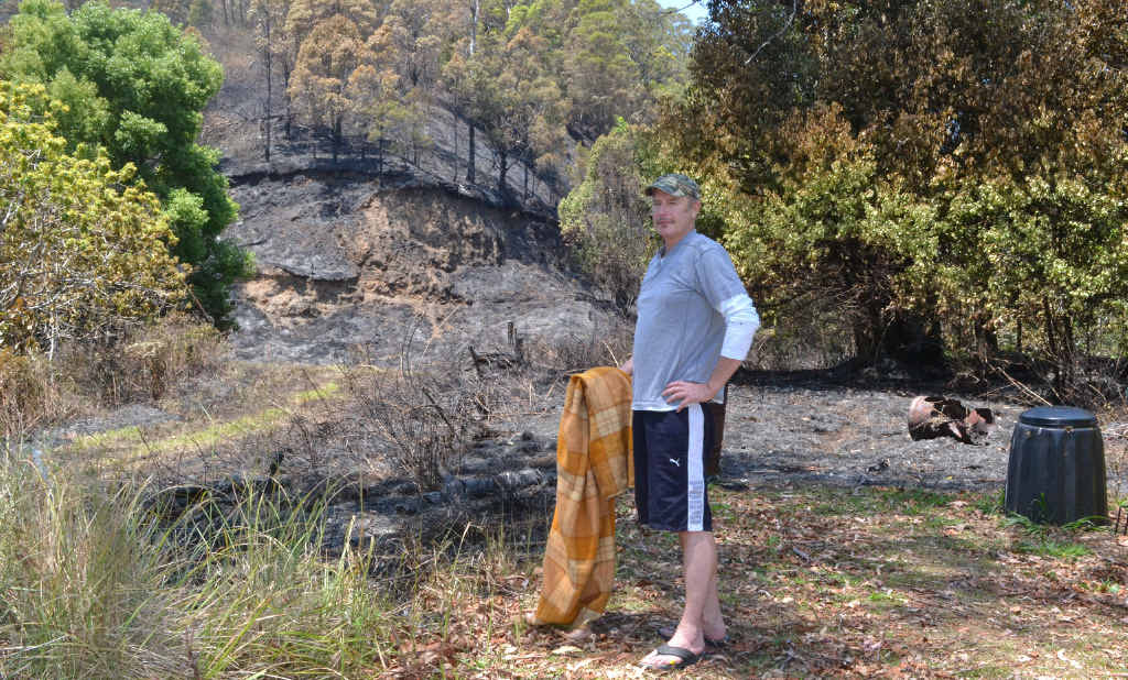 CLOSE CALL: Hamish stands at the edge of his Tuntable Creek Rd property showing how close Wednesday night’s fire came. The blanket is what he used to keep the fire at bay. Below is another picture of the fire. CLOSE CALL: Hamish stands at the edge of his Tuntable Creek Rd property showing how close Wednesday night’s fire came. The blanket is what he used to keep the fire at bay. Below is another picture of the fire.