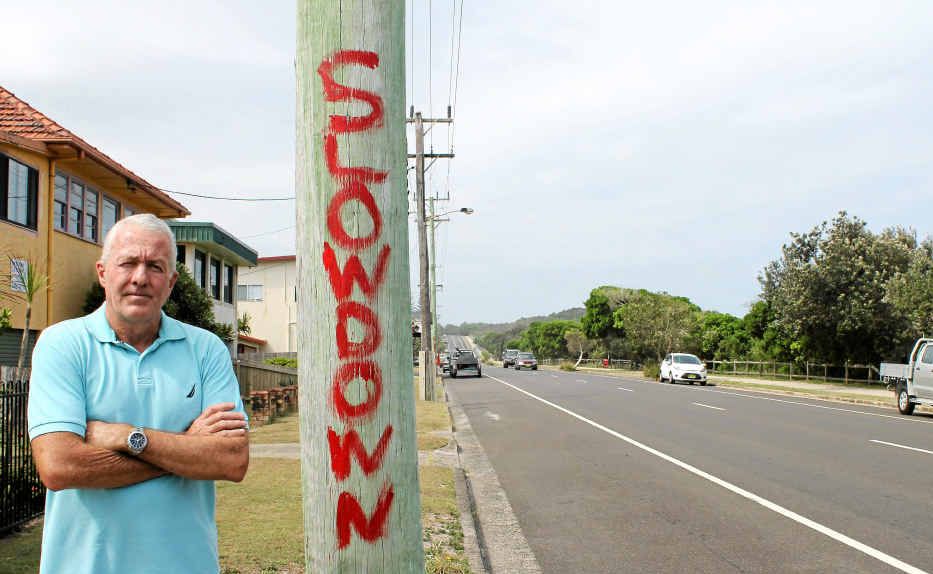 CLEAR MESSAGE: Local resident James Warren and one of the telegraph poles on Shelly Beach Rd with the words “Slow down” painted on them. CLEAR MESSAGE: Local resident James Warren and one of the telegraph poles on Shelly Beach Rd with the words “Slow down” painted on them.