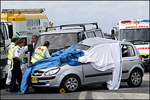 THE wrecked car in which a motorist died yesterday is shrouded in blankets as rescue workers go about their task. THE wrecked car in which a motorist died yesterday is shrouded in blankets as rescue workers go about their task.