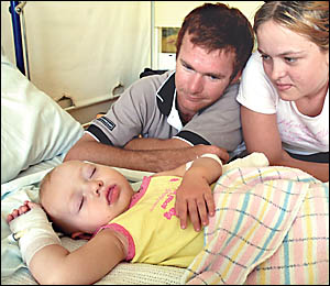 Daniel Clements and Sally Mills, from Urbenville, watch over their sleeping daughter Emi Clements, who was bitten by a black s Daniel Clements and Sally Mills, from Urbenville, watch over their sleeping daughter Emi Clements, who was bitten by a black s