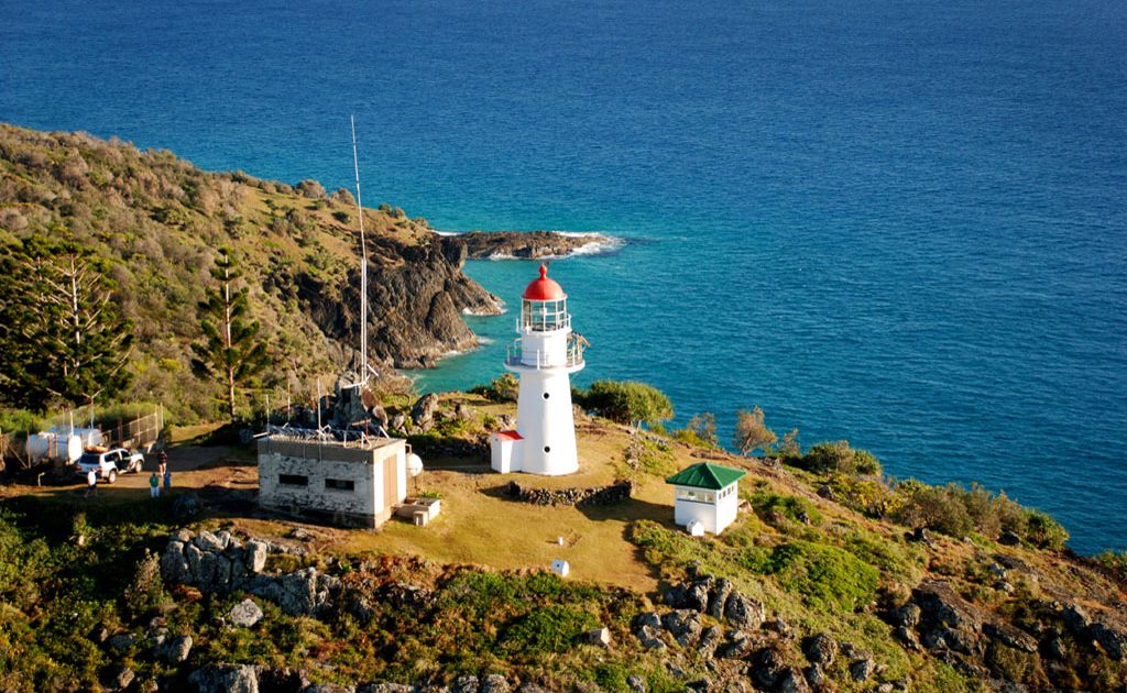 The Double Island Point Light house sits atop the rocky cliff looking over the Coral Sea. The Double Island Point Light house sits atop the rocky cliff looking over the Coral Sea.