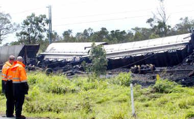 Queensland Rail staff survey the wreckage of a coal train which derailed near Stanwell. Heavy rained prevented the line being cleared straight away. Queensland Rail staff survey the wreckage of a coal train which derailed near Stanwell. Heavy rained prevented the line being cleared straight away.