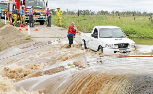 Emergency crews work to free a woman trapped in her ute on an overflowing river crossing on Kirklands Road yesterday. Emergency crews work to free a woman trapped in her ute on an overflowing river crossing on Kirklands Road yesterday.