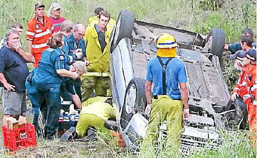 Rescue workers’ frantic efforts to save a woman trapped under her vehicle in a swollen creek yesterday afternoon. Photo: Dennis Branch AGL Rescue workers’ frantic efforts to save a woman trapped under her vehicle in a swollen creek yesterday afternoon. Photo: Dennis Branch AGL