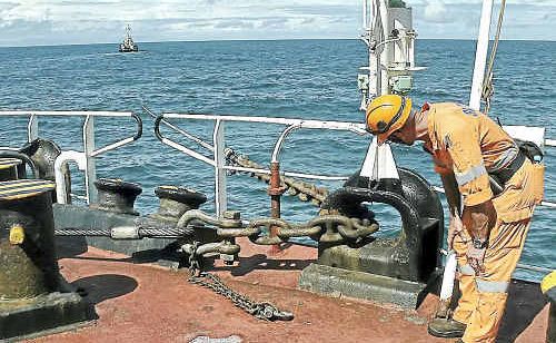 A salvage crew member inspects the chain holding the boom in place. A salvage crew member inspects the chain holding the boom in place.
