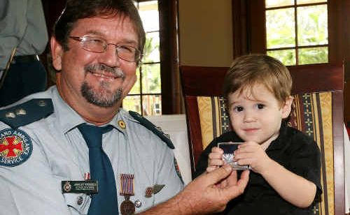 AMBO PRIDE: Emu Park’s Ashley Wessels shows grandson William Wessels his long service medal. AMBO PRIDE: Emu Park’s Ashley Wessels shows grandson William Wessels his long service medal.