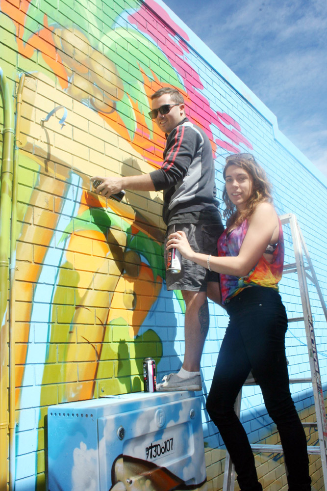 Professional mural artist Russell Fenn and assistant Callie Marshall work on transforming the alleyway wall into a giant surfing mural. Professional mural artist Russell Fenn and assistant Callie Marshall work on transforming the alleyway wall into a giant surfing mural.