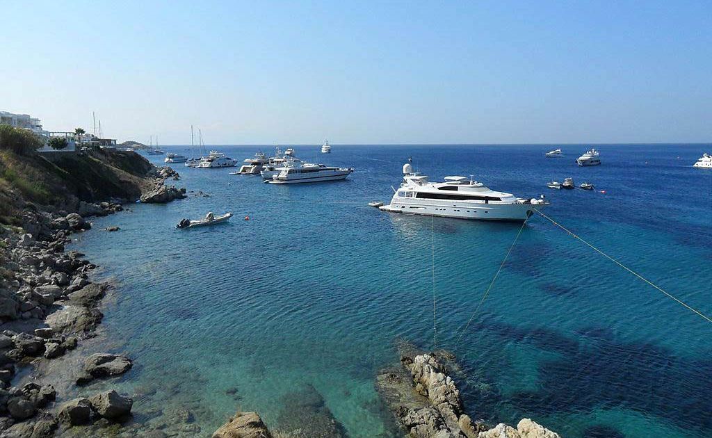 Dazzling yachts anchor in the bay at Psarou Beach. Dazzling yachts anchor in the bay at Psarou Beach.