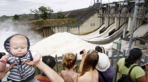 Cooper Paris, 7 months, of Rothwell gets a boost from his dad as five spillway gates open at Wivenhoe Dam. Cooper Paris, 7 months, of Rothwell gets a boost from his dad as five spillway gates open at Wivenhoe Dam.