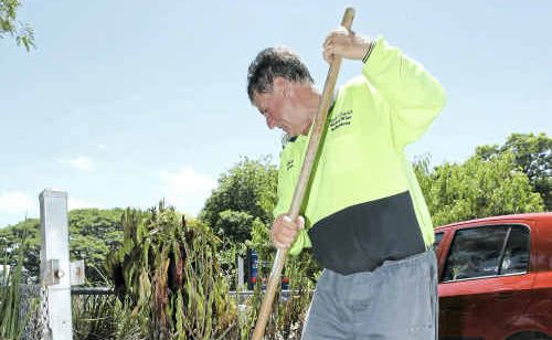 Neil Fisher removes mulch from a garden bed at Central Queensland Christian College to help the ground to dry out. Neil Fisher removes mulch from a garden bed at Central Queensland Christian College to help the ground to dry out.