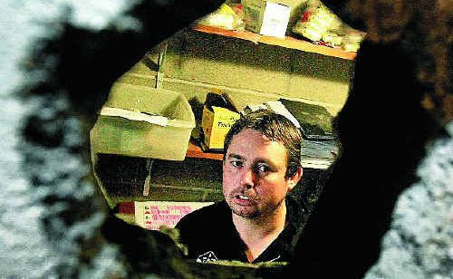 Condong Bowls Club assistant manager Scott Reading looks through the hole he and a club patron chiselled after being locked in the club’s strongroom during an armed robbery. Condong Bowls Club assistant manager Scott Reading looks through the hole he and a club patron chiselled after being locked in the club’s strongroom during an armed robbery.