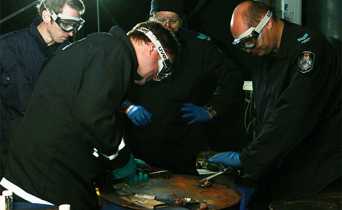 Police carry out forensic testing on the barrels of hydraulic oil seized by the AFP at the Mackay railway yard. Police carry out forensic testing on the barrels of hydraulic oil seized by the AFP at the Mackay railway yard.