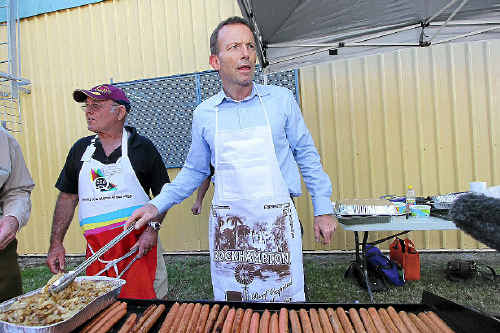 Opposition Leader Tony Abbott mans the barbecue at a sausage sizzle at the Rockhampton Showgrounds yesterday.