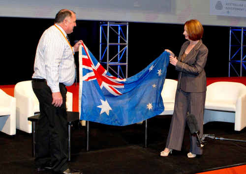 Prime Minster Julia Gillard presenting Lockyer Valley mayor Cr Steve Jones with the mud-streaked Australian flag salvaged from Grantham after the January floods. 