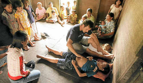 HELPING HAND: SurfAid founder and medical director Dr Dave Jenkins treats a Mentawai woman. HELPING HAND: SurfAid founder and medical director Dr Dave Jenkins treats a Mentawai woman.