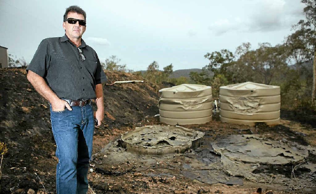 Brian Smith stands above his water tanks that were burnt in the wildfires along Yeppoon Rd over the weekend. Brian Smith stands above his water tanks that were burnt in the wildfires along Yeppoon Rd over the weekend.