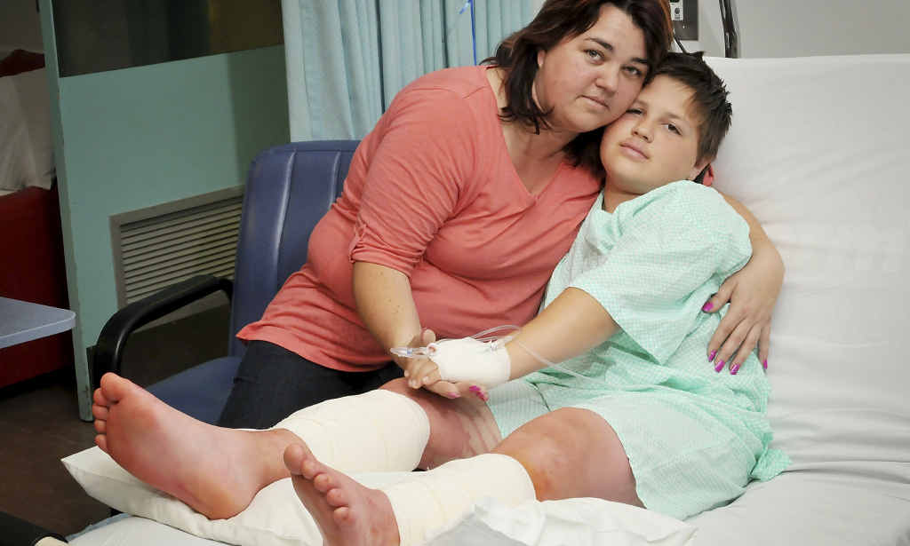 Samantha Cornell comforts her son Wayne in Toowoomba Hospital yesterday after he had surgery on deep dog bite wounds. Samantha Cornell comforts her son Wayne in Toowoomba Hospital yesterday after he had surgery on deep dog bite wounds.