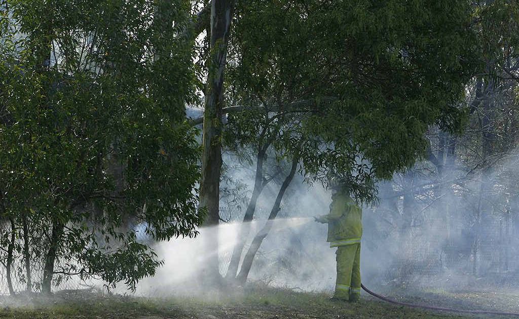 A firefighter hoses down an abandoned property on Grace St in Wulkuraka, where residents were evacuated because of asbestos released from the burning building. A firefighter hoses down an abandoned property on Grace St in Wulkuraka, where residents were evacuated because of asbestos released from the burning building.