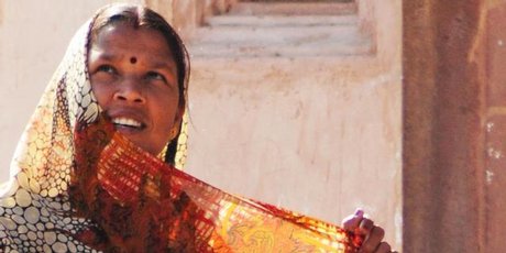 A woman adjusts her sari in the sun. A woman adjusts her sari in the sun.