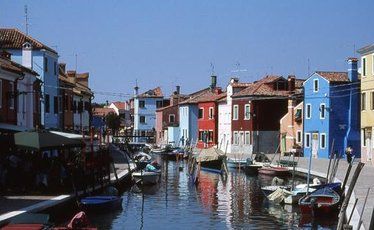 Brightly painted houses reflect in the peaceful canals of Venice's Burano Island. Brightly painted houses reflect in the peaceful canals of Venice's Burano Island.