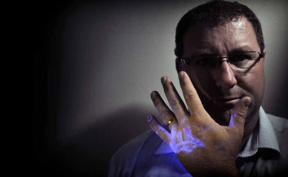 Jeffre Murray, of DNA Security Solutions, shows off the effect the security system’s spray has on human skin when viewed under a special black light. Jeffre Murray, of DNA Security Solutions, shows off the effect the security system’s spray has on human skin when viewed under a special black light.