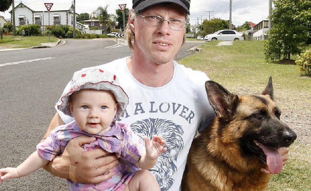 Ken Knebel with his seven-month-old daughter Samara and dog Sina on the street where they were attacked by two big dogs in Ipswich. Ken Knebel with his seven-month-old daughter Samara and dog Sina on the street where they were attacked by two big dogs in Ipswich.