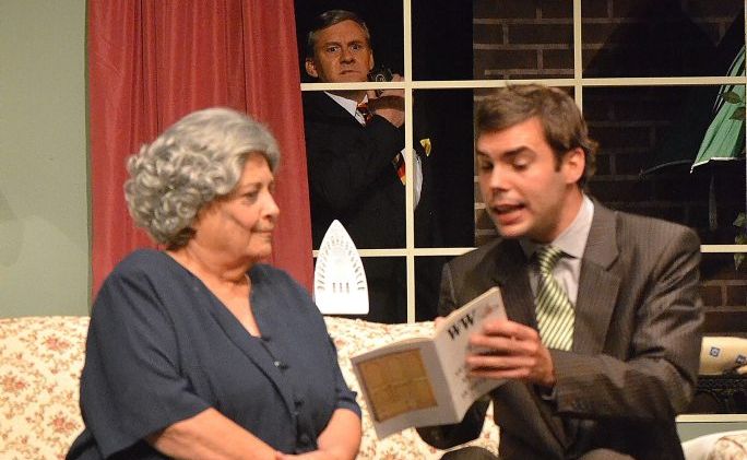 Salesman Desmond Donohoe (Mark Phythian) looks through the window as another salesman Warren Wallis (Ben Ferwerda on right) gets the jump on him with his sales pitch to May Archer (Lyn Hodgson).