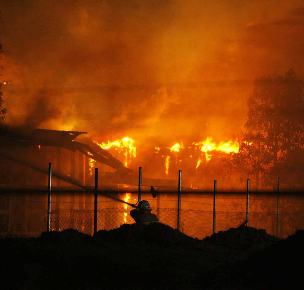 A firefighter hoses the flames which engulfed buildings at the old North Ipswich Railway Workshops. 