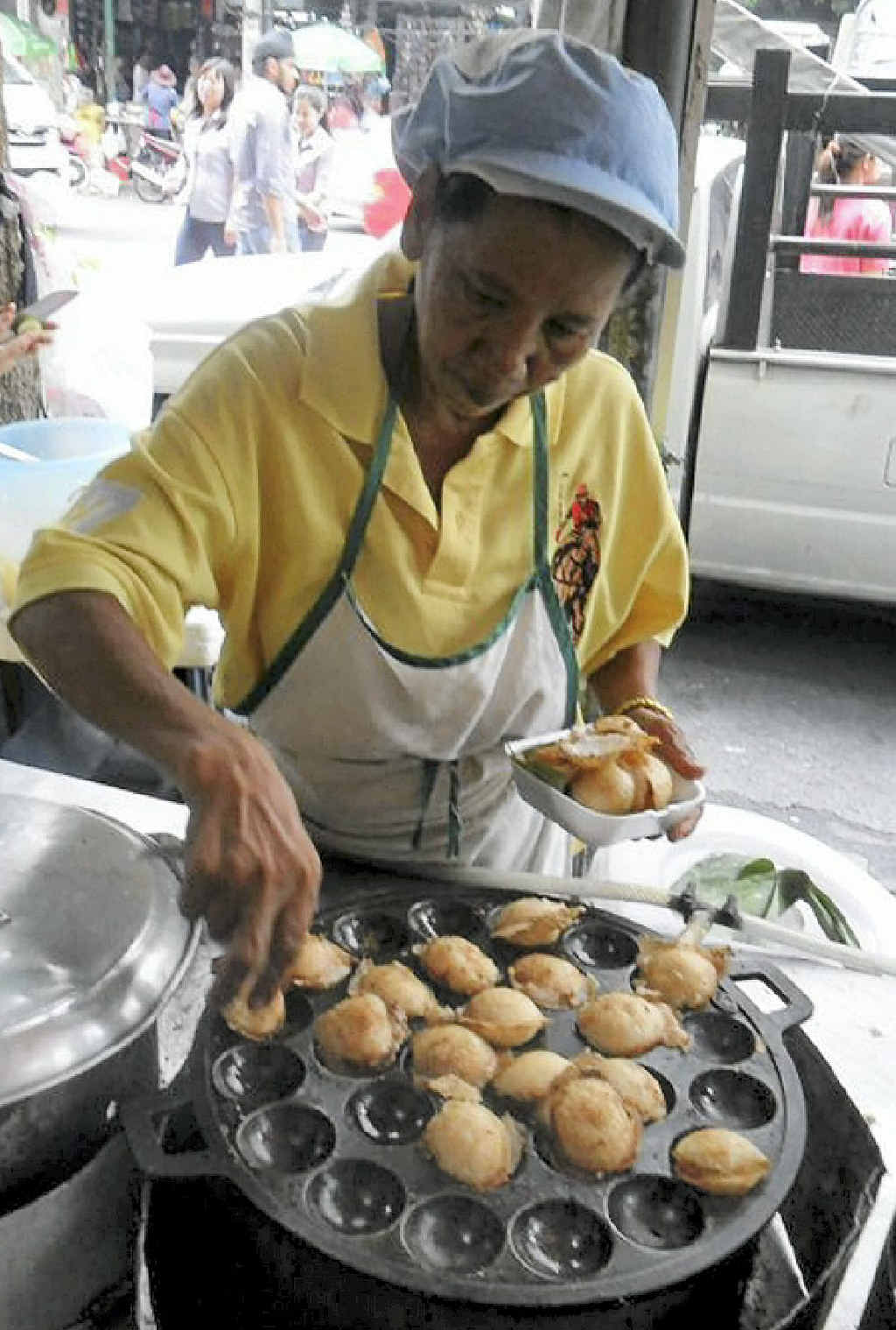 A woman makes a mountainous heap of crispy chicken on the streets of Bangkok. A woman makes a mountainous heap of crispy chicken on the streets of Bangkok.