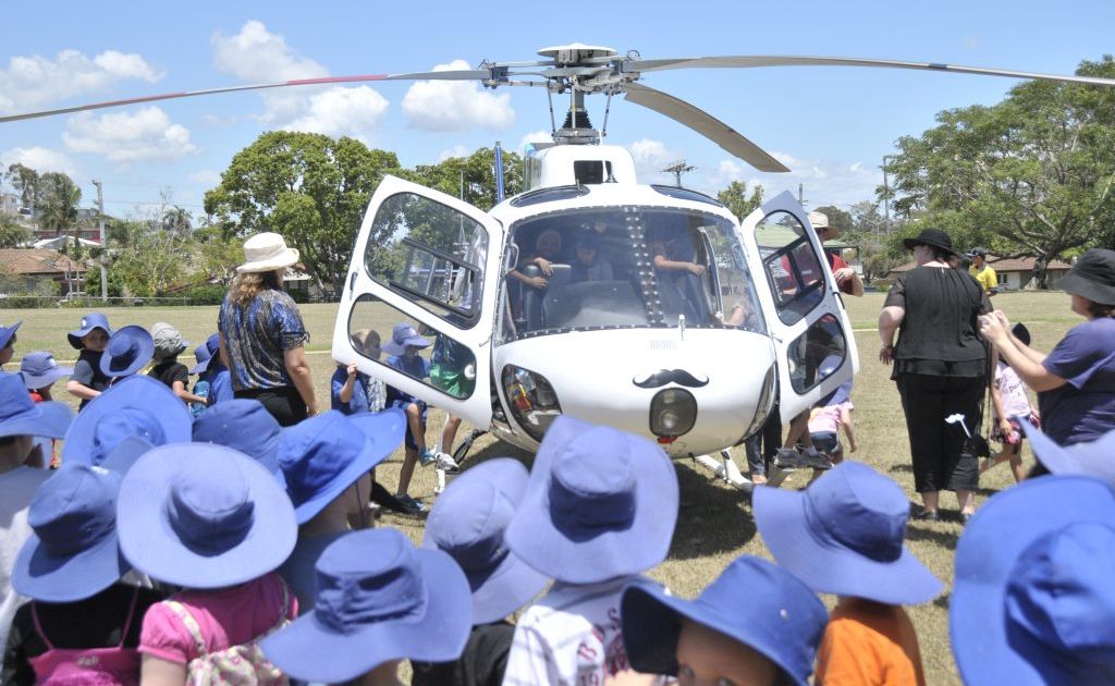 A moustache-wearing helicopter lands at Gladstone West State School to help celebrate Movember. A moustache-wearing helicopter lands at Gladstone West State School to help celebrate Movember.