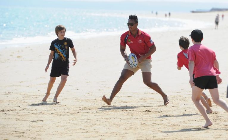 Reds fullback UJ Seuteni takes on the local lads in a game of touch rugby at Torquay Beach. Reds fullback UJ Seuteni takes on the local lads in a game of touch rugby at Torquay Beach.