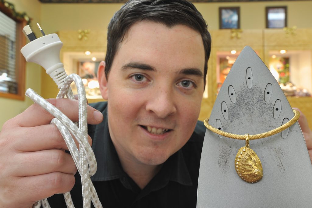Gemmologist Matthew Gray from Haigh's Jewellers with a 9ct yellow gold diamond set shell worth $2700 on a 9ct yellow gold mesh link chain worth $2100 and the practical iron. Gemmologist Matthew Gray from Haigh's Jewellers with a 9ct yellow gold diamond set shell worth $2700 on a 9ct yellow gold mesh link chain worth $2100 and the practical iron.