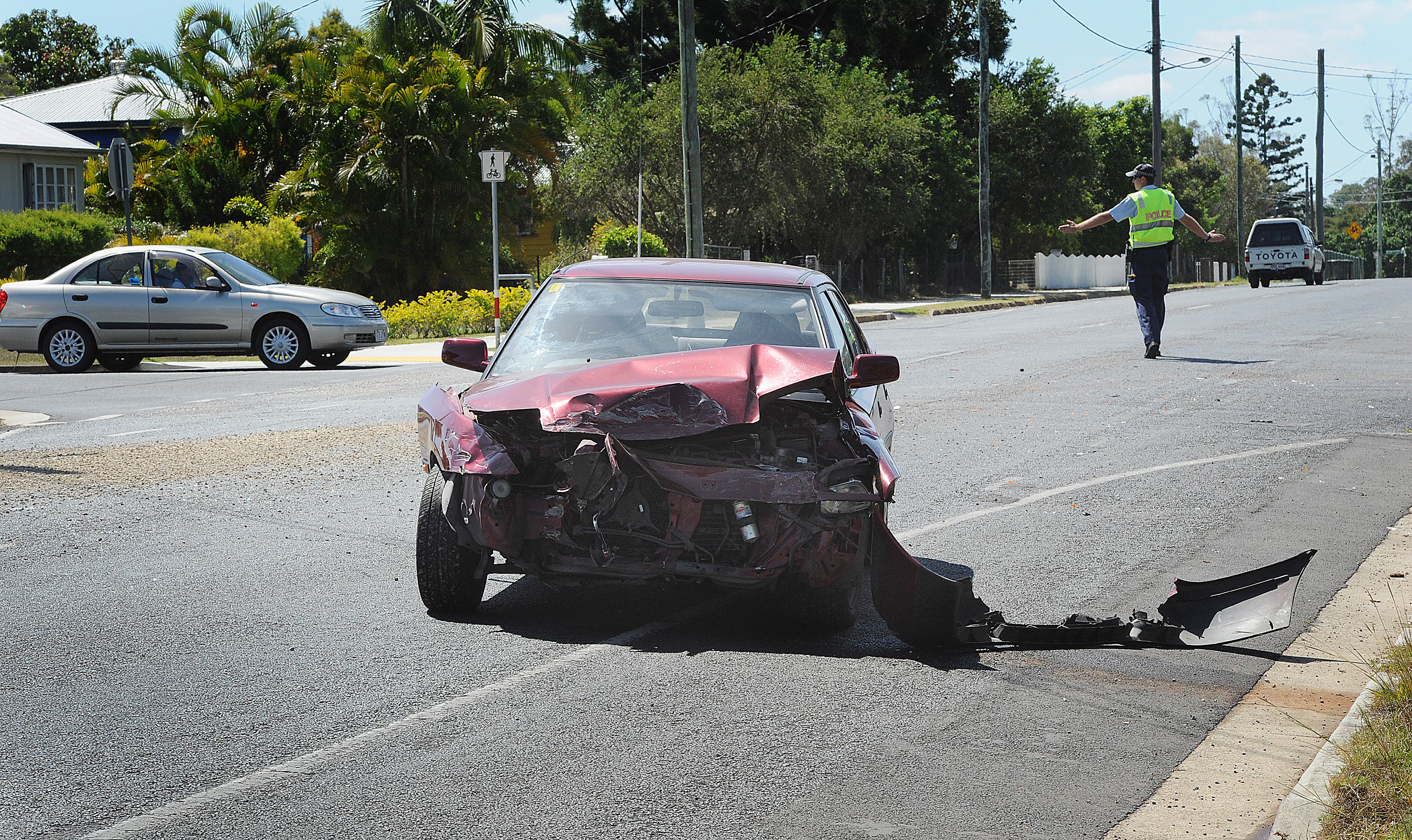 A police officer directs traffic after a crash between a car and a landscaping truck at the corner of Alice and Morning Sts in Maryborough.