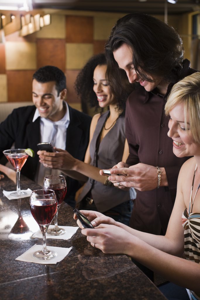 Friends texting at bar together Friends texting at bar together