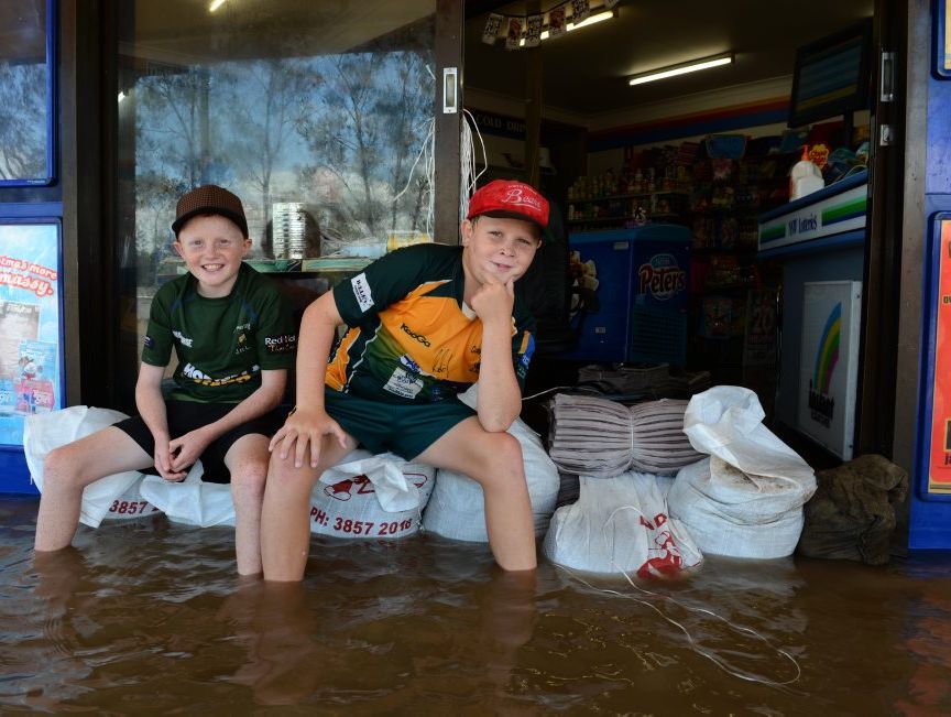 Taylor and Parker Bryant on some sand bags in front of Chinderah News.