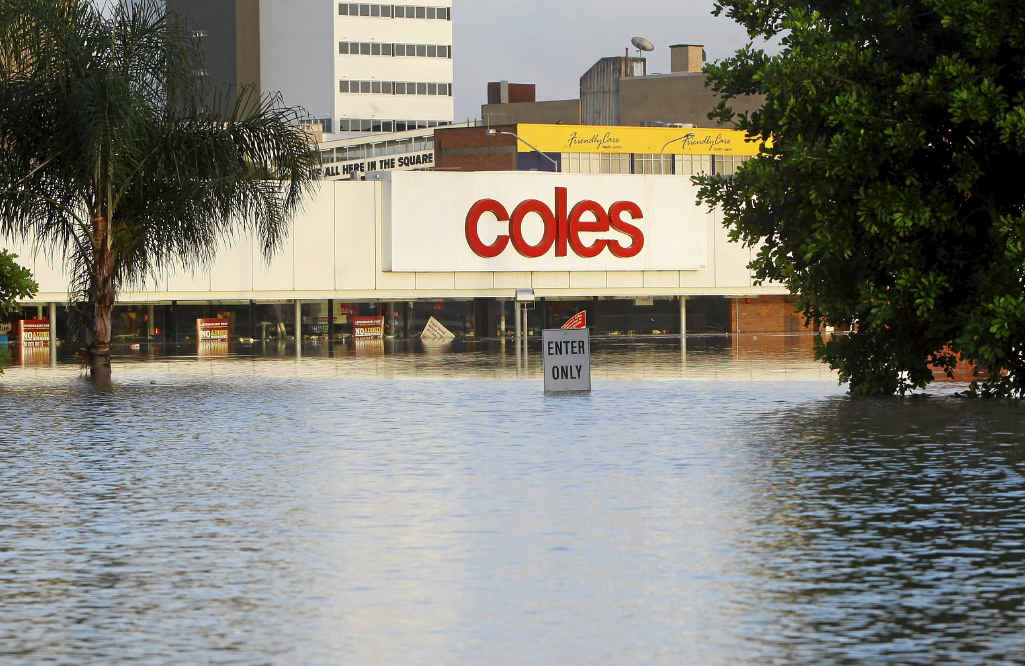The Coles store under water in the 2011 floods and (right) the site after its demolition in November of the same year. The Coles store under water in the 2011 floods and (right) the site after its demolition in November of the same year.
