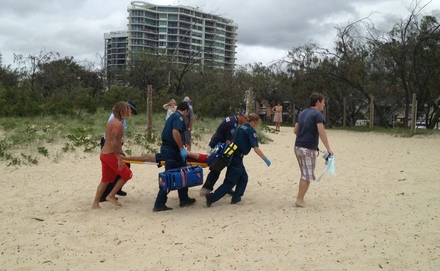 The kayaker is carried across the beach to an ambulance. The kayaker is carried across the beach to an ambulance.