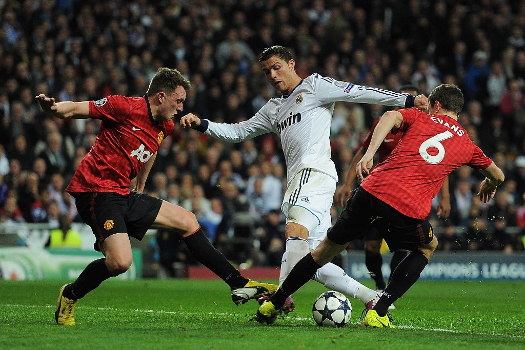 Cristiano Ronaldo of Real Madrid is put under pressure by Jonny Evans and Phil Jones of Manchester United during the UEFA Champions League Round of 16 first leg match between Real Madrid and Manchester United at Estadio Santiago Bernabeu on February 13, 2013 in Madrid, Spain. Cristiano Ronaldo of Real Madrid is put under pressure by Jonny Evans and Phil Jones of Manchester United during the UEFA Champions League Round of 16 first leg match between Real Madrid and Manchester United at Estadio Santiago Bernabeu on February 13, 2013 in Madrid, Spain.
