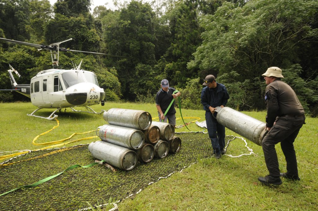 Delivering gas cylinders by air from Repentance creek hall (From Left) Land owner Bruce Stewart, Pilots Wayne McIntosh, and Tim Latimer. Photo Doug Eaton / The Northern Star Delivering gas cylinders by air from Repentance creek hall (From Left) Land owner Bruce Stewart, Pilots Wayne McIntosh, and Tim Latimer. Photo Doug Eaton / The Northern Star