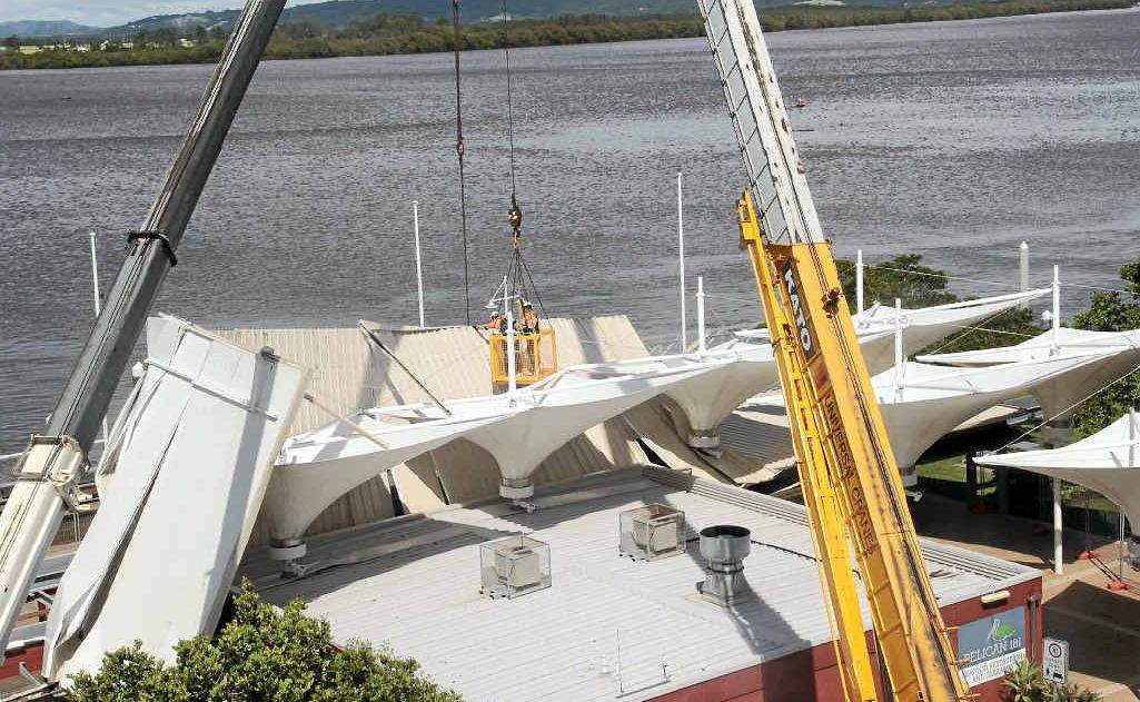 Cranes work to secure the roof of the Pelican restaurant in Ballina, that was torn away by strong winds on Friday. Cranes work to secure the roof of the Pelican restaurant in Ballina, that was torn away by strong winds on Friday.