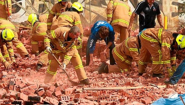 Firemen and workers frantically dig into the fallen brick wall.
Firemen and workers frantically dig into the fallen brick wall.