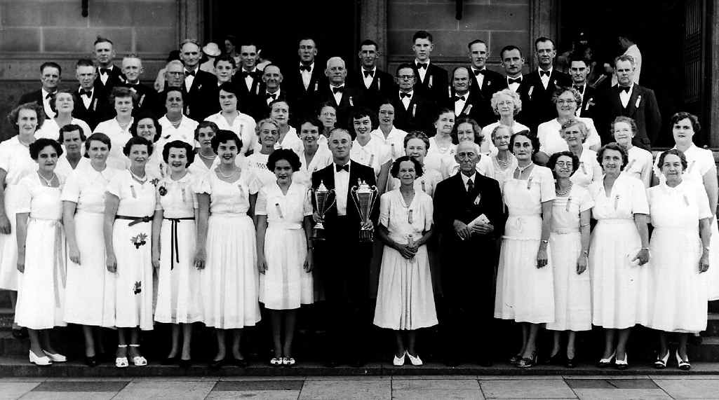 FROM METAL TO MUSIC: Mr Tom Bird (fifth from the right, front) stands proudly with the Silkstone/Booval Choral Union after winning trophies at the Queensland Eisteddfod in Brisbane (c1950s). FROM METAL TO MUSIC: Mr Tom Bird (fifth from the right, front) stands proudly with the Silkstone/Booval Choral Union after winning trophies at the Queensland Eisteddfod in Brisbane (c1950s).