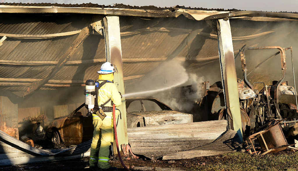 A Gympie Fire and Rescue officer dampens down the scene of yesterday’s shed fire on Bath Rd. A Gympie Fire and Rescue officer dampens down the scene of yesterday’s shed fire on Bath Rd.