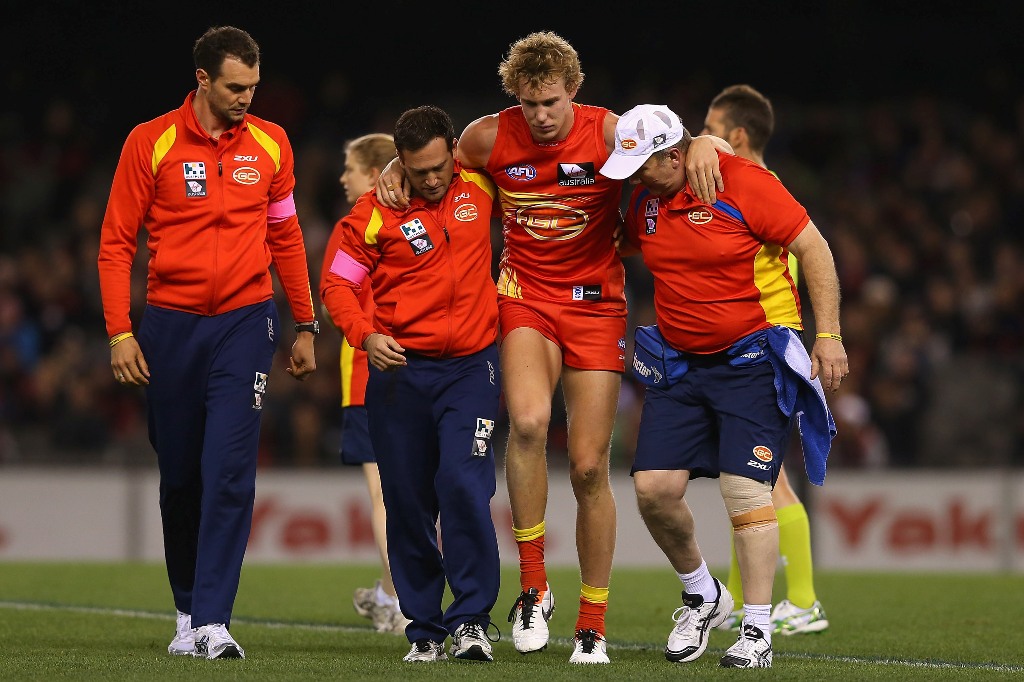 Tom Lynch of the Suns is helped from the ground after colliding with Jake Melksham of the Bombers during the round 12 AFL match between the Essendon Bombers and the Gold Coast Suns at Etihad Stadium on June 15, 2013 in Melbourne, Australia. Tom Lynch of the Suns is helped from the ground after colliding with Jake Melksham of the Bombers during the round 12 AFL match between the Essendon Bombers and the Gold Coast Suns at Etihad Stadium on June 15, 2013 in Melbourne, Australia.