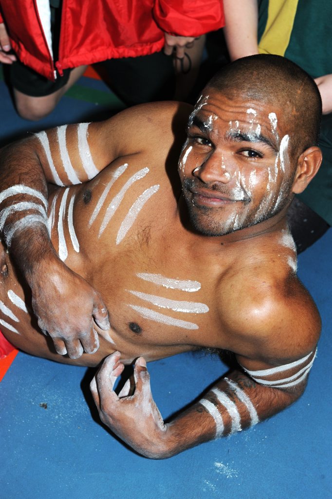 Malcolm Burns, in a kangaroo pose, is part of Burunga-m Gambay (Learning Together) with schoolchildren at a University of Southern Queensland event. 