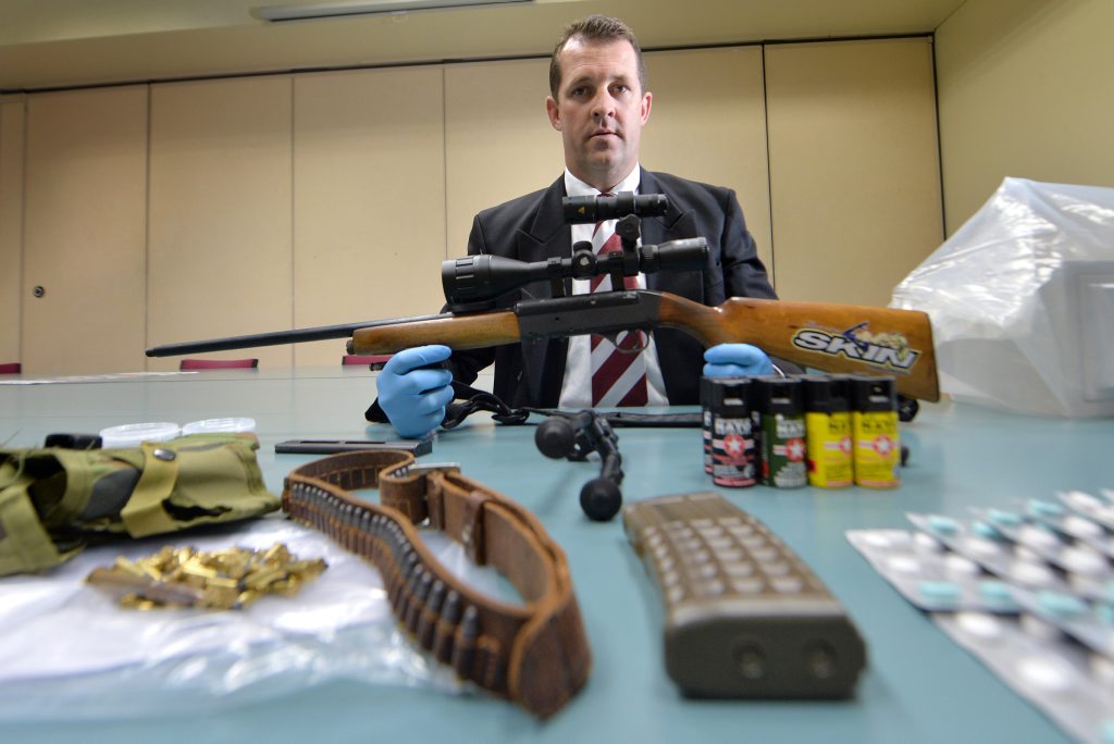 Gladstone Detective Senior Sergeant Luke Peachy with a semi-automatic weapon and other drug-related items seized during two separate raids on Wednesday. Gladstone Detective Senior Sergeant Luke Peachy with a semi-automatic weapon and other drug-related items seized during two separate raids on Wednesday.