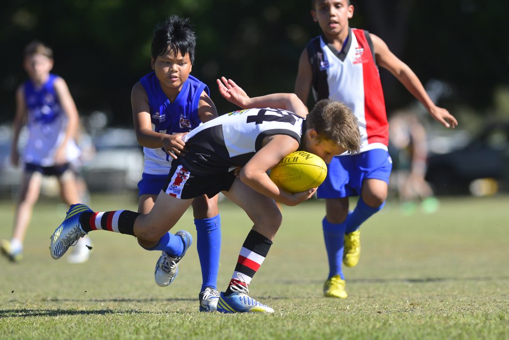 BITS Saints player Liam Croft stays strong with the ball in a match against Brothers Roos at the Junior Cluster Day on August 4.