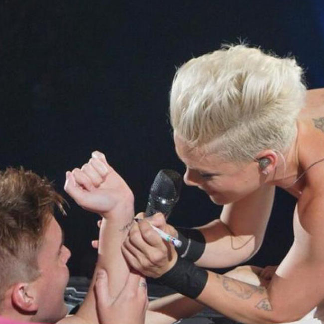 Pink signing her superfan's wrist. Pink signing her superfan's wrist.